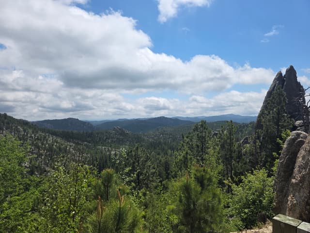 A granite spire above forested hills in the Black Hills