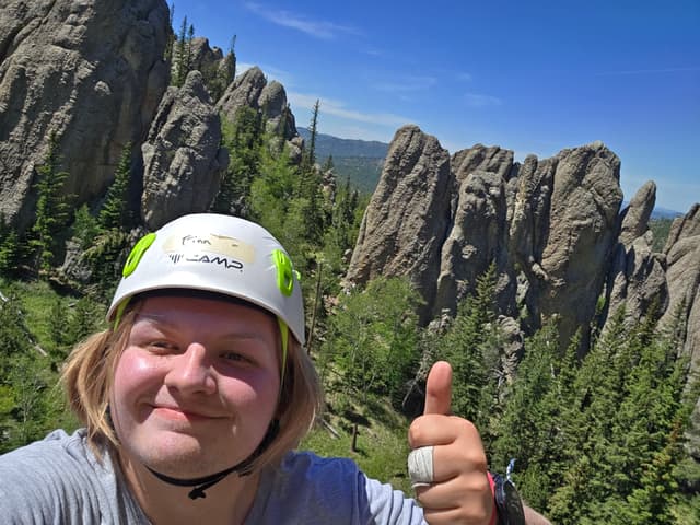 Finn in a climbing helmet in front of granite spires