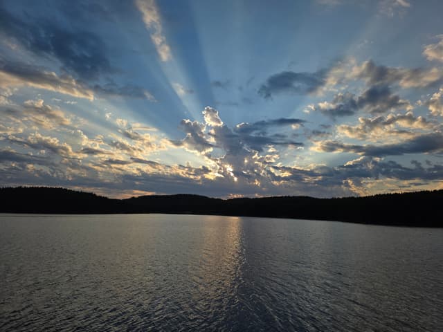 Sun rays fanning out over a still lake