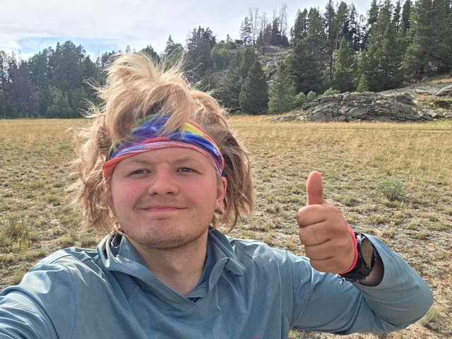 Finn in a headband giving a thumbs up in a sunny meadow
