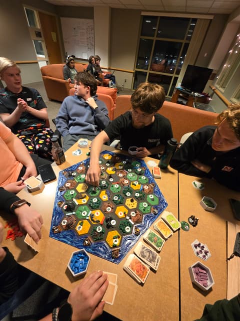 Friends gathered around a Catan board