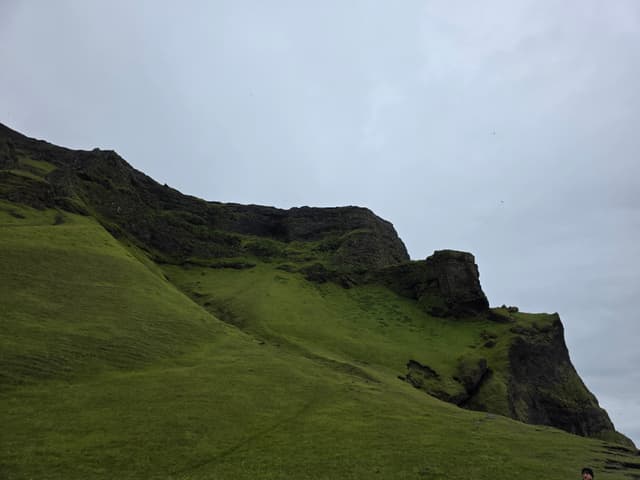 Steep moss-green cliffs under an overcast sky