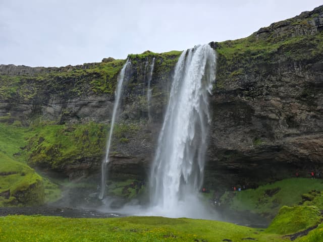 Seljalandsfoss and its smaller neighbor falling over a mossy cliff