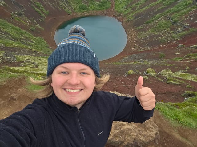 Finn in a bobble hat above the blue crater lake at Kerið
