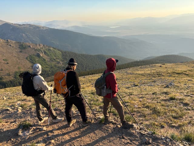 Four hikers looking out over mountains at sunrise