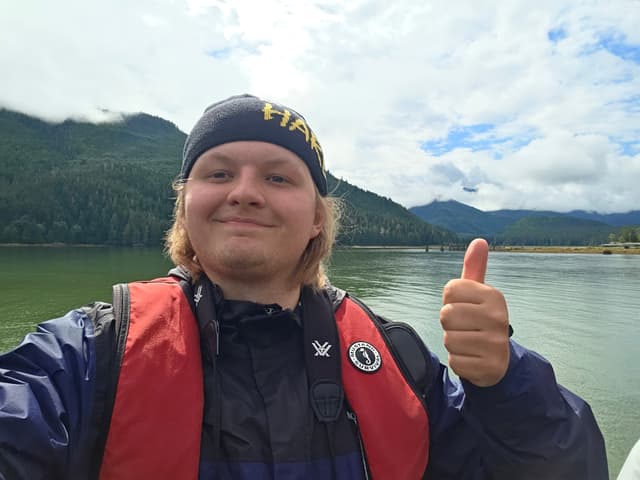 Finn in a life jacket giving a thumbs up on a boat